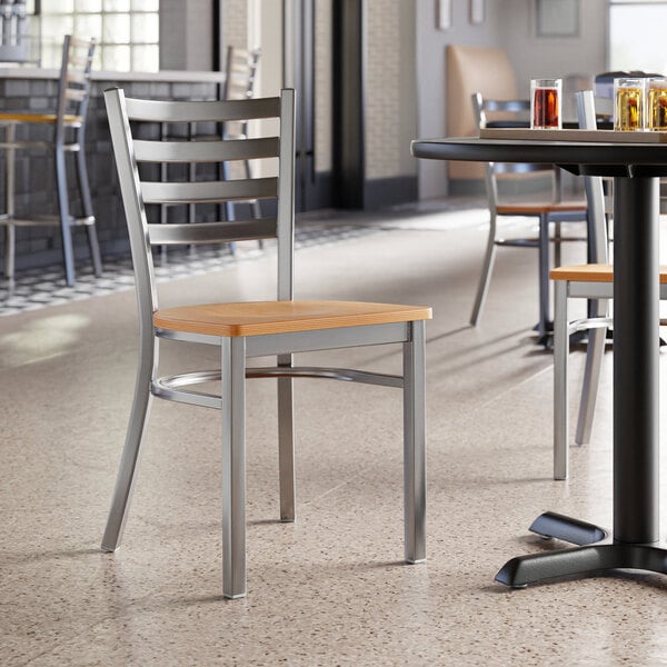 A Lancaster Table & Seating ladder back chair with a natural wood seat at a table in a restaurant.