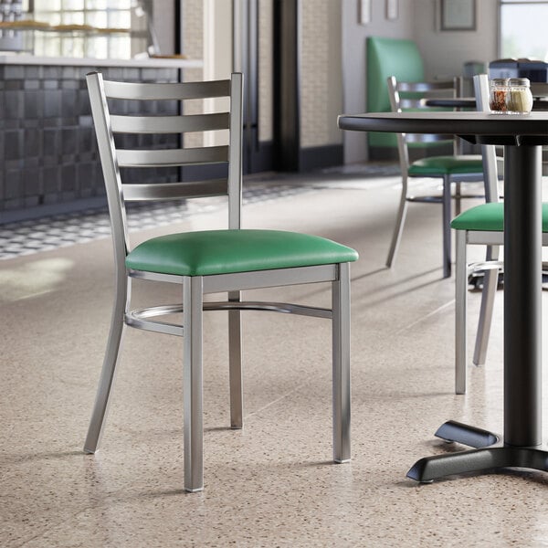 A Lancaster Table & Seating green vinyl padded chair seat on a ladder back chair.