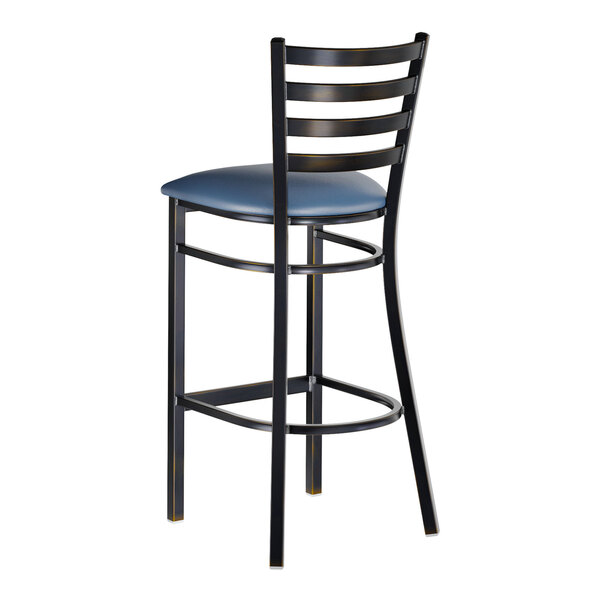A metal bar stool with a ladder back design and a navy blue vinyl padded seat.