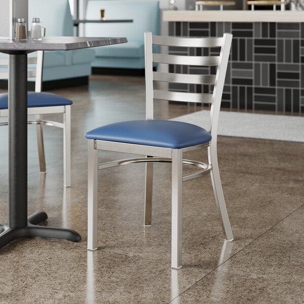 Two Lancaster Table & Seating white chairs with navy blue padded seats at a table in a restaurant.