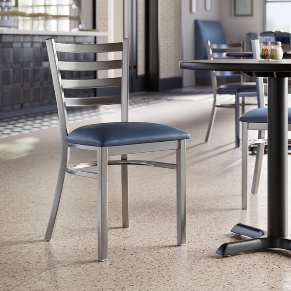 A Lancaster Table & Seating ladder back chair with a detached navy vinyl padded seat.