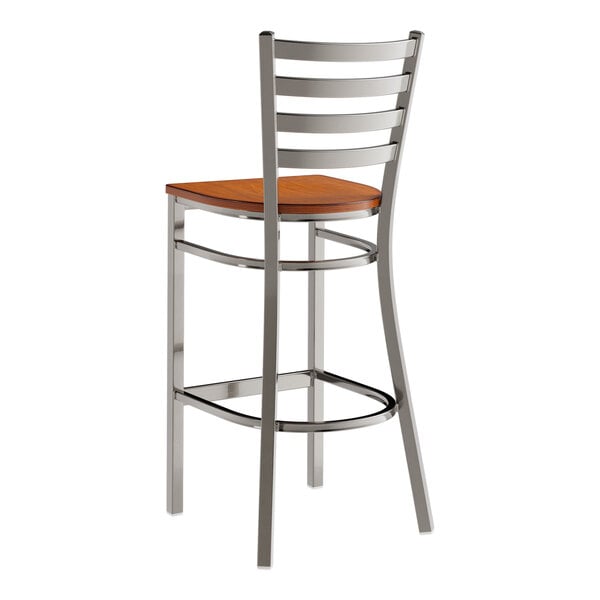 A metal bar stool with a ladder back design and an antique walnut wood seat.