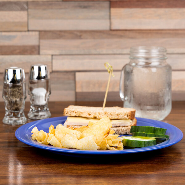 A Carlisle Ocean Blue melamine plate with food on it on a table.