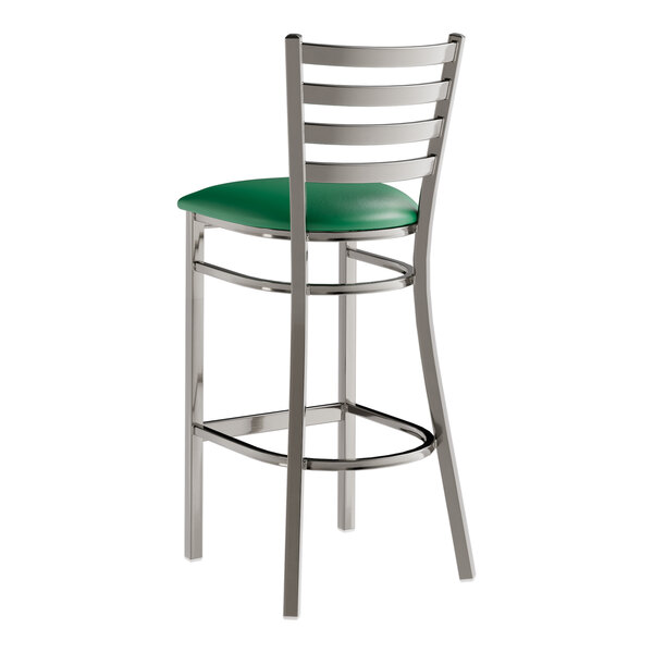 A metal bar stool with a ladder back design and a green vinyl padded seat.