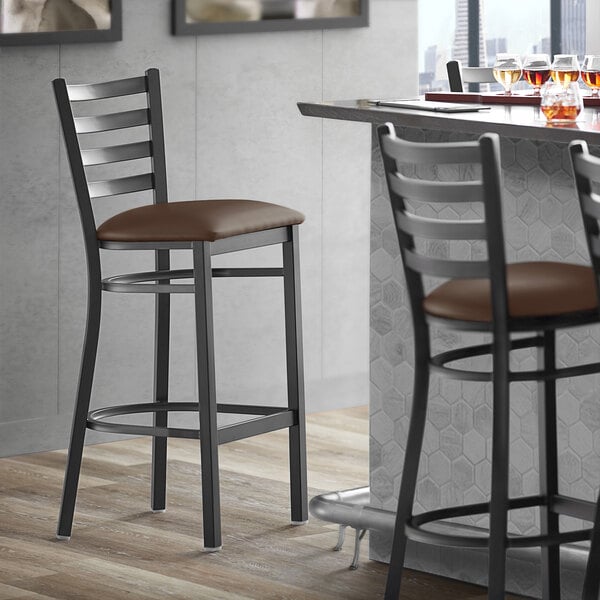 A Lancaster Table & Seating black metal restaurant bar stool with a dark brown cushioned seat.