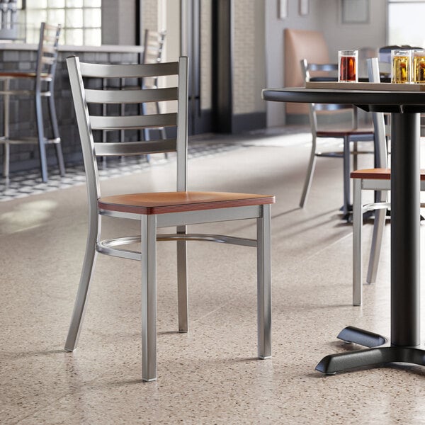 A Lancaster Table & Seating ladder back chair with a wooden seat at a table in a restaurant.