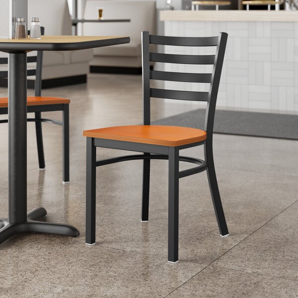 A Lancaster Table & Seating black finish chair with a cherry wood seat at a table in a restaurant.