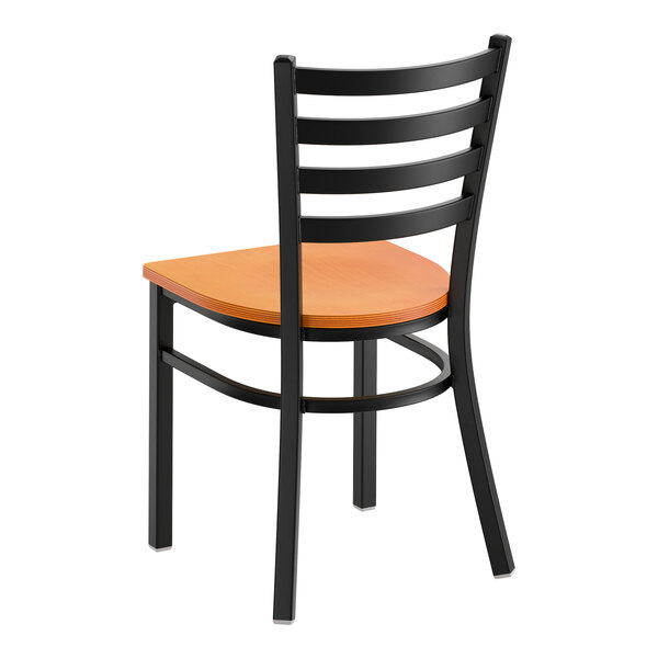 A black metal ladder back chair with a cherry wood seat.