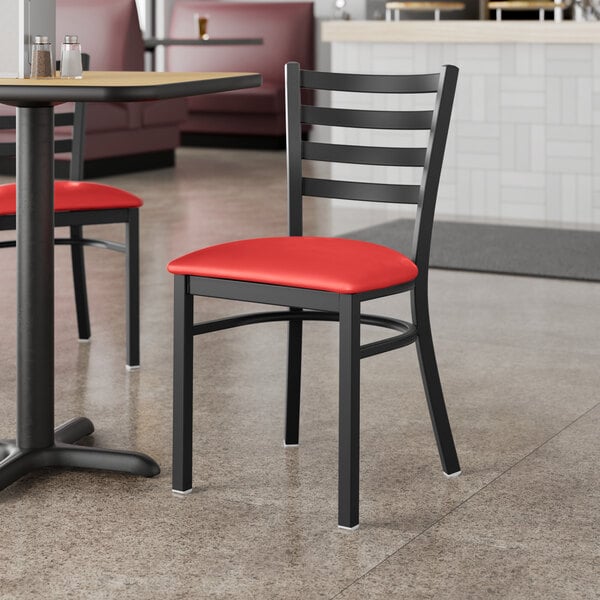 A Lancaster Table & Seating black metal restaurant chair with red vinyl padding on the seat.