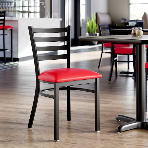 A black ladder back chair with a red vinyl padded seat.