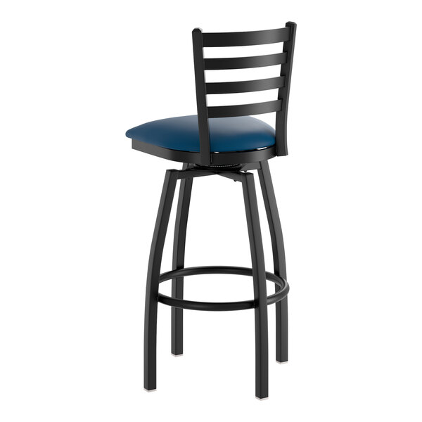 A black metal swivel bar stool with a ladder back and a navy blue vinyl padded seat.