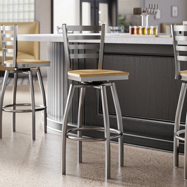 A group of Lancaster Table & Seating Ladder Back Swivel Bar Stools with driftwood seats at a kitchen counter.