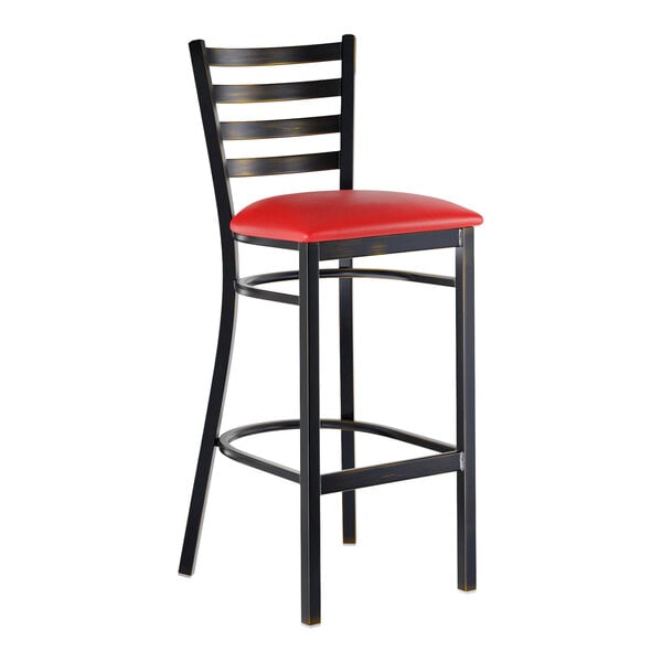 A metal bar stool with a ladder back design, distressed copper finish, and a red vinyl padded seat.