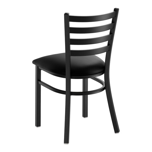 A black ladder back chair with a padded black vinyl seat.