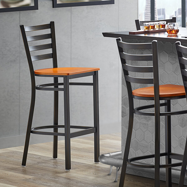 A Lancaster Table & Seating distressed copper finish ladder back bar stool with a cherry wood seat.