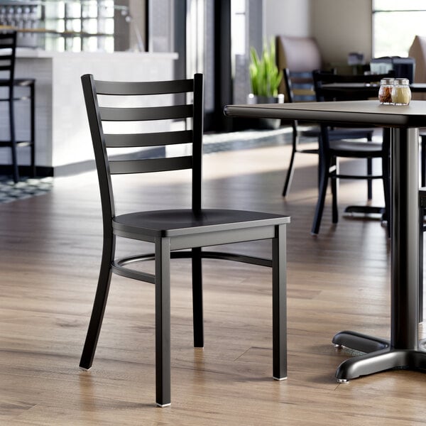 A black ladder back chair with a black wood seat, designed for dining or restaurant use.