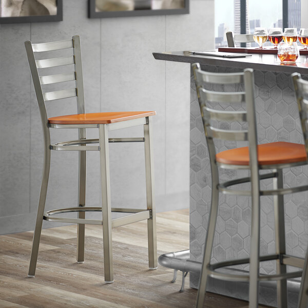 A Lancaster Table & Seating Ladder Back Bar Stool with Cherry Wood Seat next to a counter.