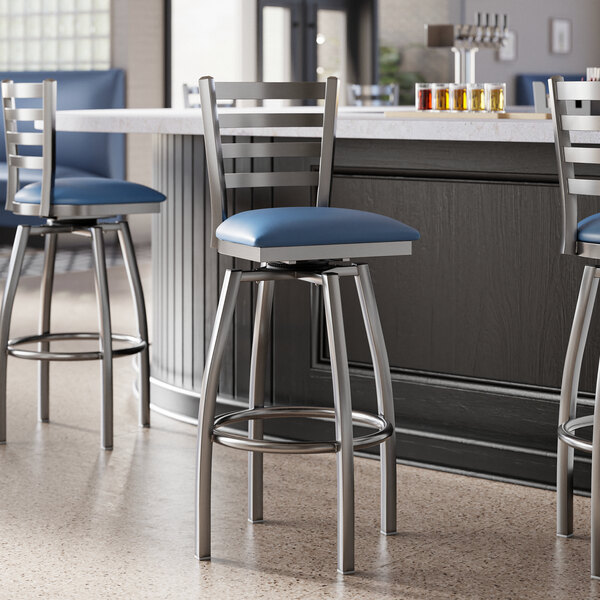 Lancaster Table & Seating clear coat finish ladder back swivel bar stools with navy vinyl padded seats.