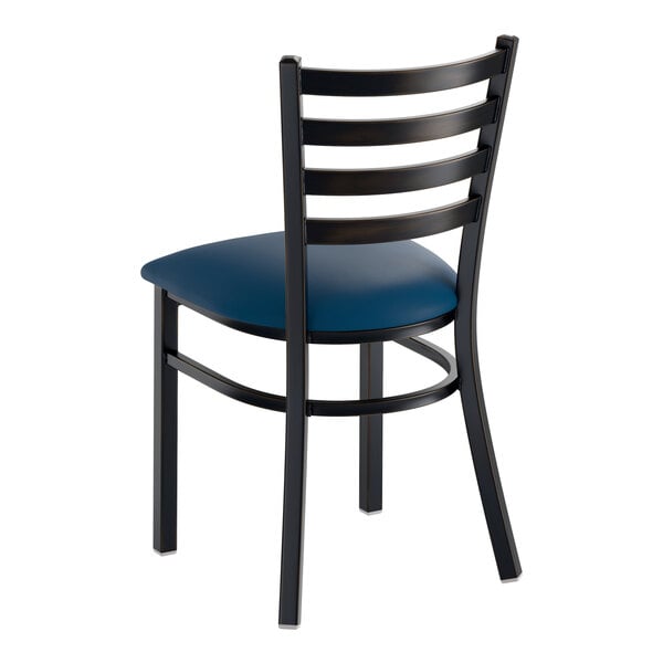 A metal ladder back chair with a navy blue vinyl padded seat and a distressed copper finish.