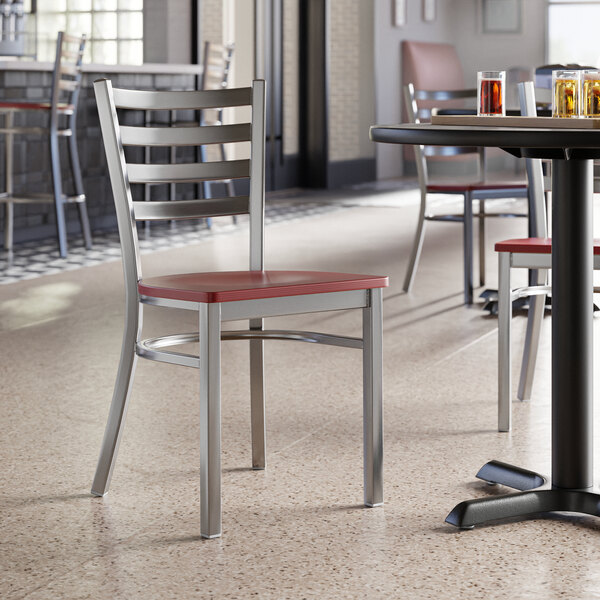 A Lancaster Table & Seating ladder back chair with a mahogany seat at a table in a restaurant.