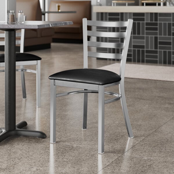 A Lancaster Table & Seating black vinyl padded restaurant chair with silver legs.