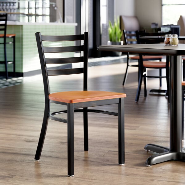 A ladder back chair with a distressed copper finish and a cherry wood seat.