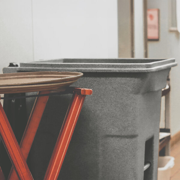 A large graystone rectangular wheeled trash can with a lid.