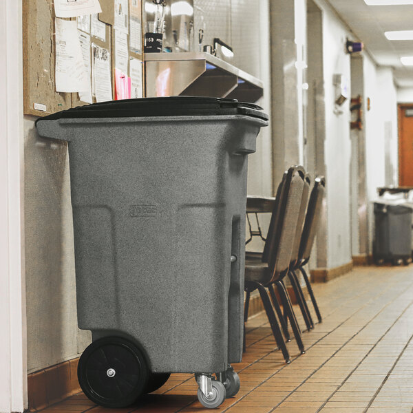 A large graystone rectangular wheeled trash can with a lid.