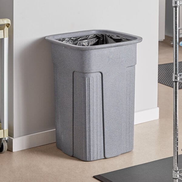 A Toter Slimline gray plastic trash can sits in front of a door in a corporate office cafeteria.