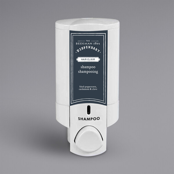 A white Dispenser Amenities wall mounted shower dispenser with black accents and a Beekman label.