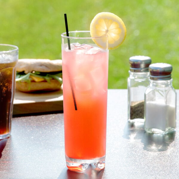 A Roc N' Roll SAN plastic Collins glass filled with pink liquid and a straw with a lemon slice.