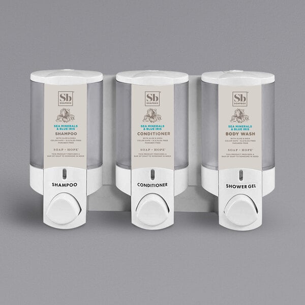 A white Dispenser Amenities Aviva 3-chamber wall mounted soap dispenser with translucent bottles.