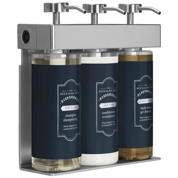 A black wall-mounted Dispenser Amenities SOLera shower dispenser with three oval bottles labeled Beekman.