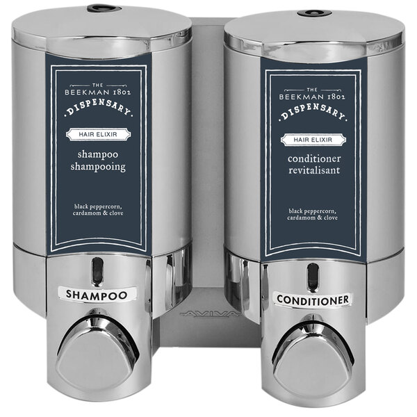 A chrome wall-mounted dispenser with two satin silver bottles with Beekman labels.