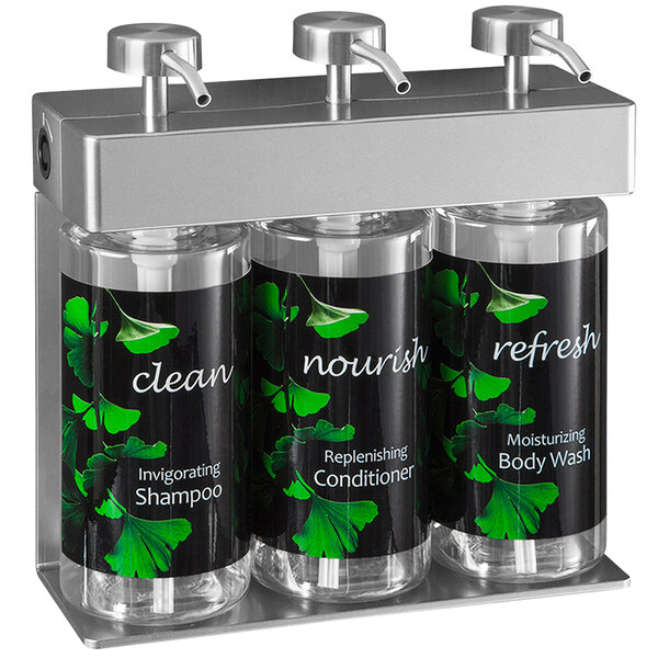 A black wall-mounted dispenser with three oval bottles and ginkgo leaf labels.