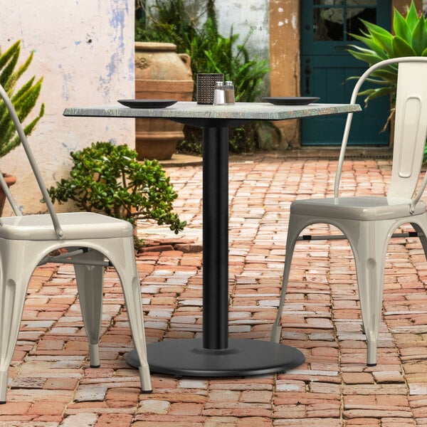A Lancaster Table & Seating black outdoor table base with chairs on a brick patio.