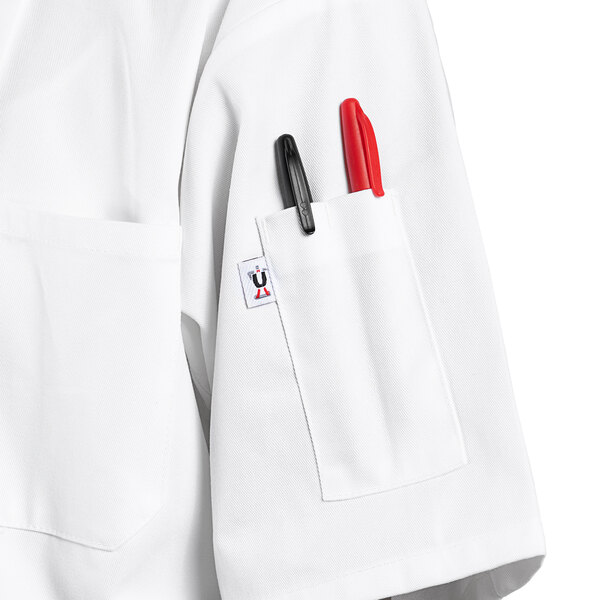 A white Uncommon Chef short sleeve chef coat with two red pens in the pocket.