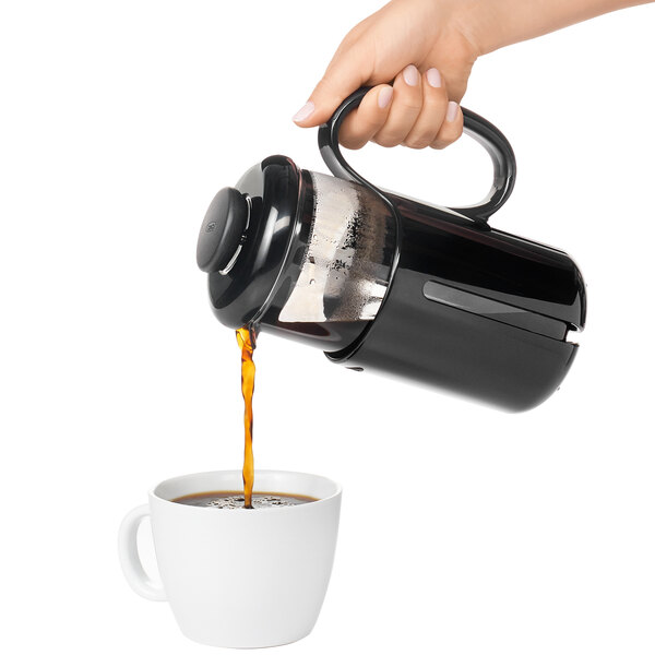 a hand pouring coffee into a coffee pot