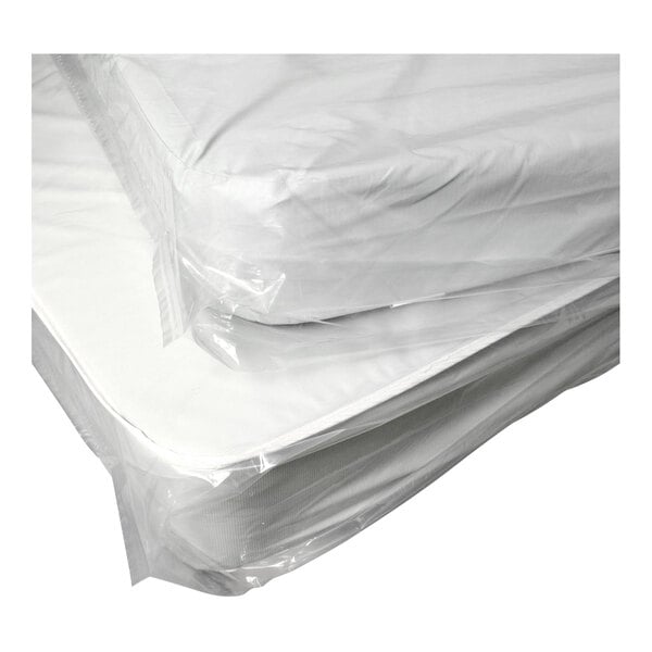 Two mattresses wrapped in clear plastic covers, stacked on top of each other.