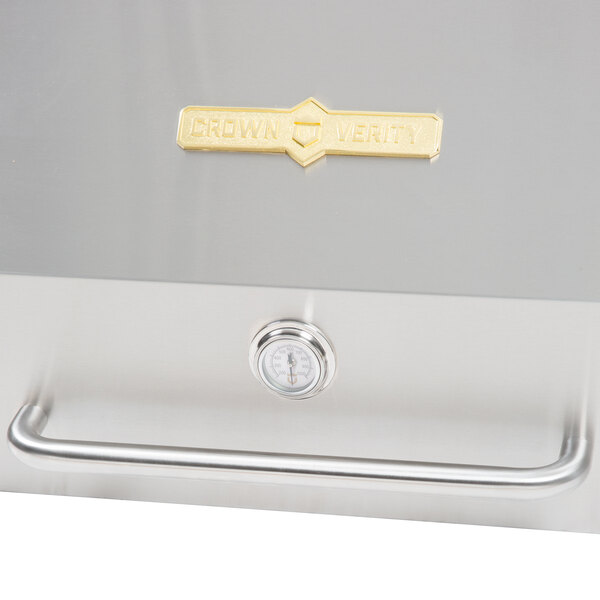 A stainless steel Crown Verity roll dome cover with a gold handle.