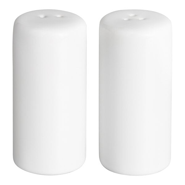 Two white cylindrical containers with small holes on top, likely used as salt and pepper shakers.