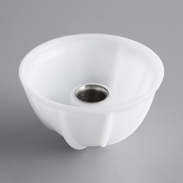 A white plastic bowl with a circular metal reamer with a hole in it.