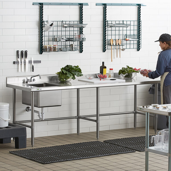 A woman in a school kitchen using a Regency cross brace on a work table.