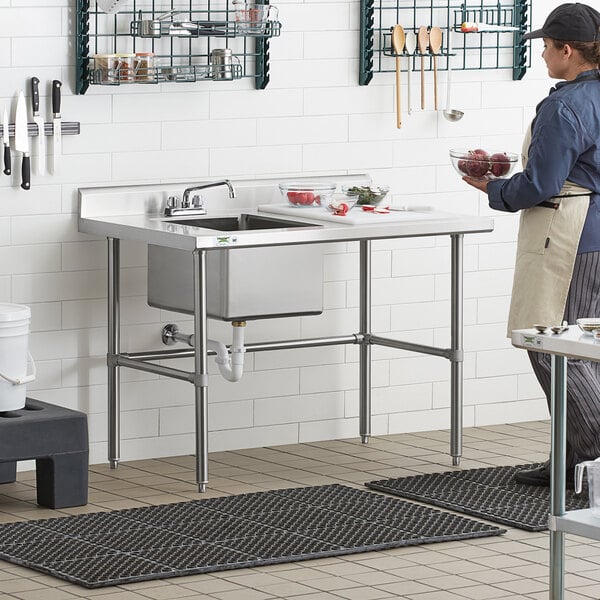 A woman standing in a professional kitchen with a Regency cross brace on a work table.