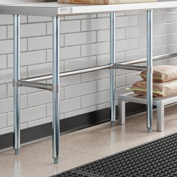 A Regency stainless steel work table with a Regency metal shelf holding a stack of brown bags.