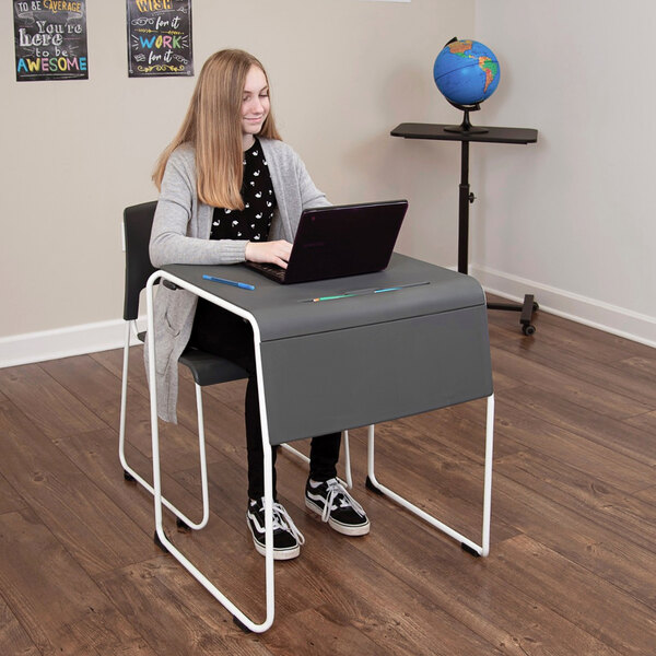 A person sitting at a Luxor desk using a laptop.