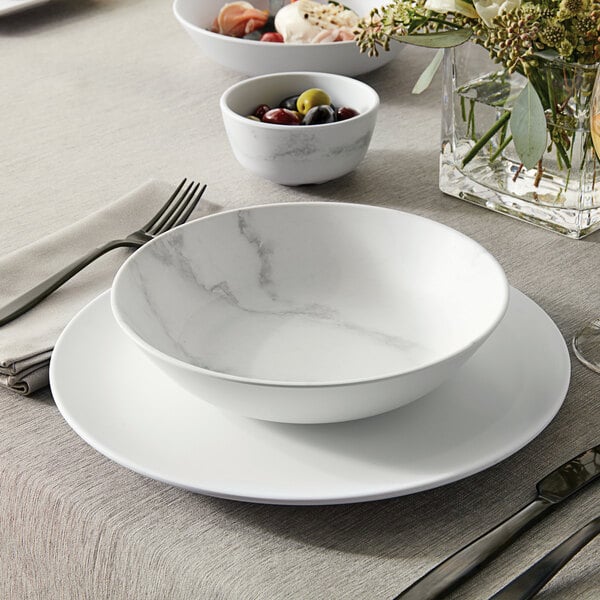 An American Metalcraft marble melamine bowl with a marble pattern on a table with a bowl of olives.