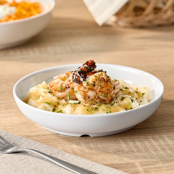 A white round shallow melamine bowl with a 14 oz. capacity, shown holding a serving of food.