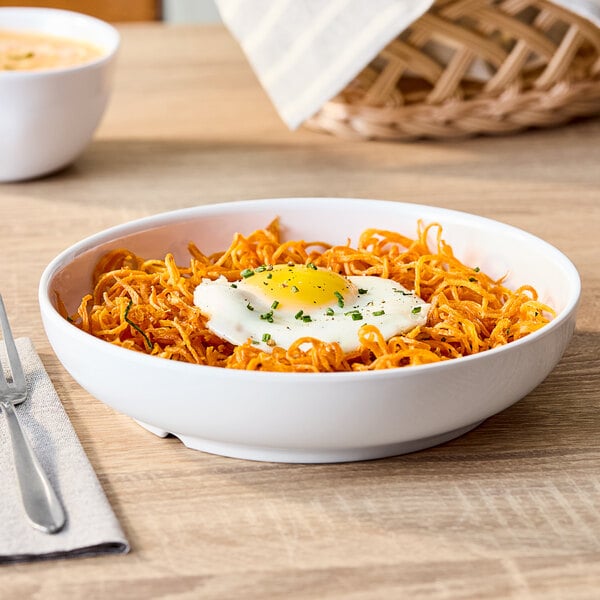 A white round shallow melamine bowl filled with food, shown on a wooden table.
