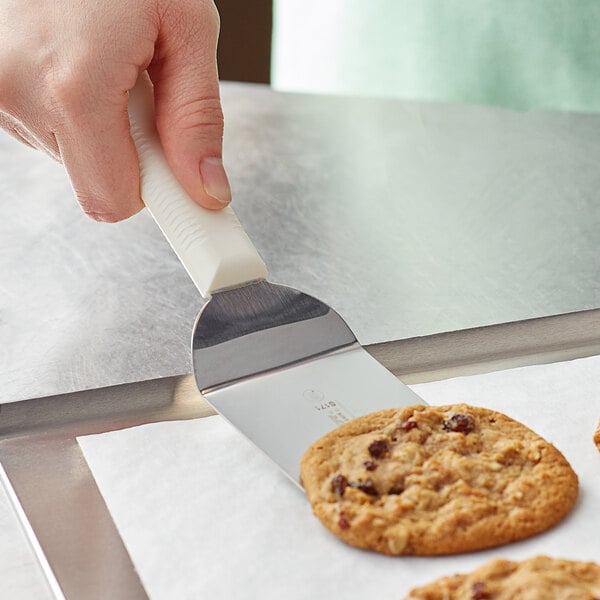 A hand holding a Dexter-Russell Sani-Safe mini turner over cookies.